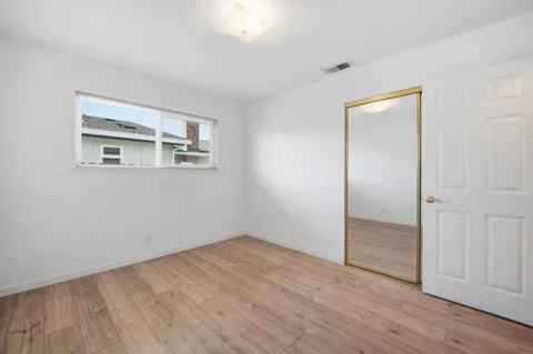 a view of empty room with wooden floor and fan