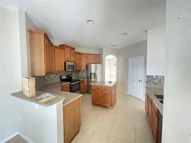 a kitchen with stainless steel appliances granite countertop a stove top oven a sink a refrigerator and white cabinets with wooden floor