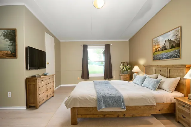 a spacious bedroom with a bed and a flat screen tv