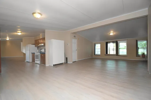 a view of a livingroom with a kitchen stove a refrigerator with wooden floor and a window