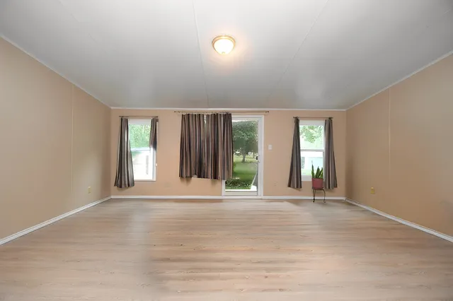 a view of an empty room with window and wooden floor