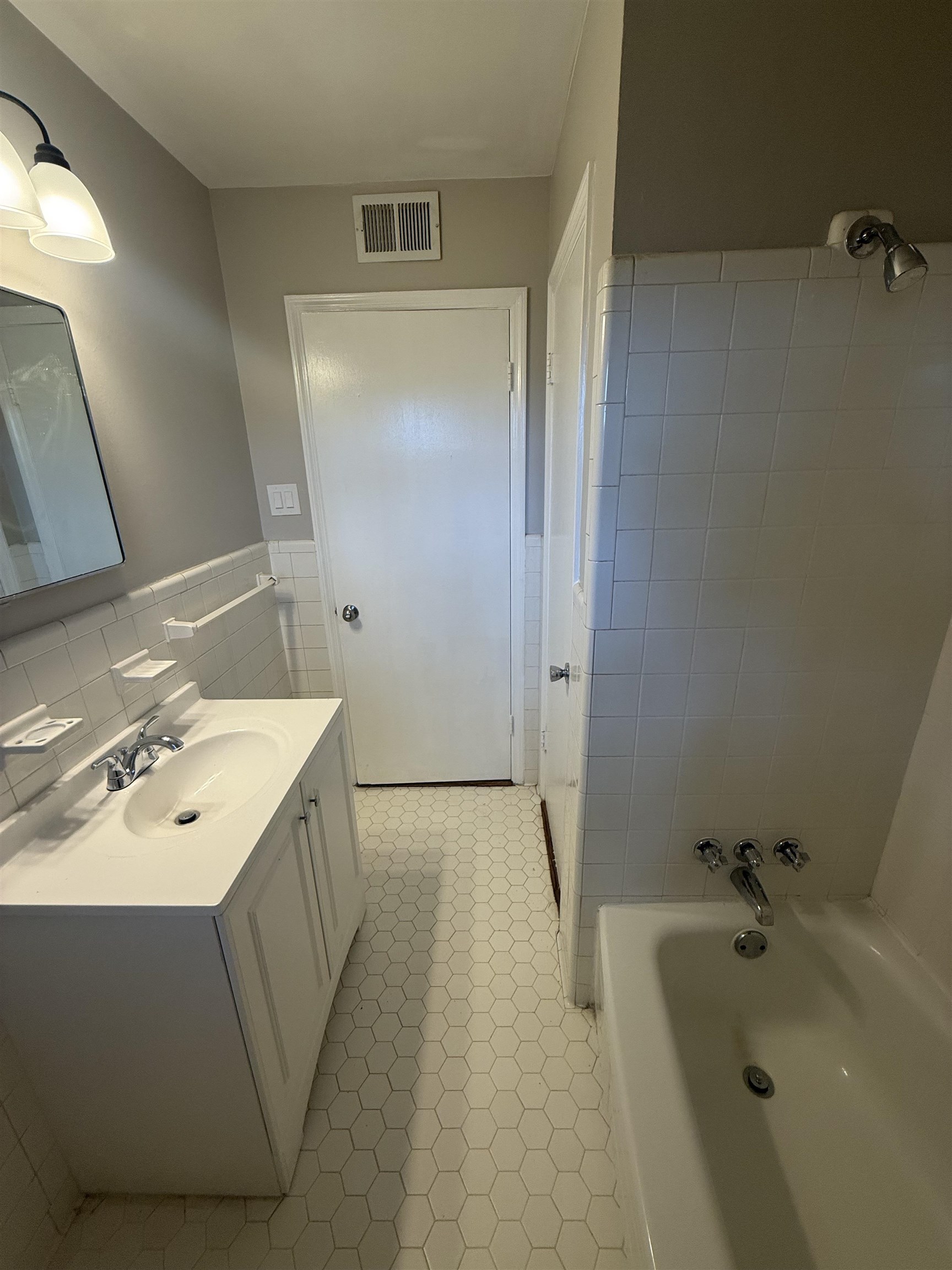 1918 Cherry Road Memphis, TN 38117 - Photo 17 of 26 Bathroom featuring a white vanity with integrated sink, chrome faucet, wall-mounted mirror, and hexagonal floor tiling