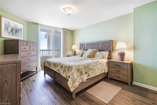 a bedroom with a bed a mirror on dresser and a window