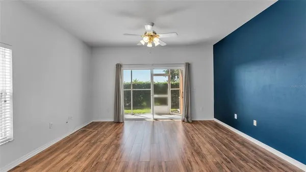 a view of empty room with wooden floor and fan