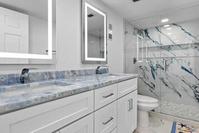 a bathroom with a granite countertop sink a toilet and a shower