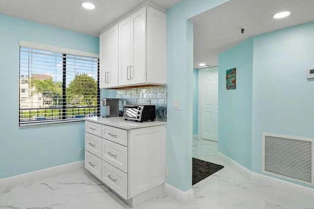 a kitchen with white cabinets and window