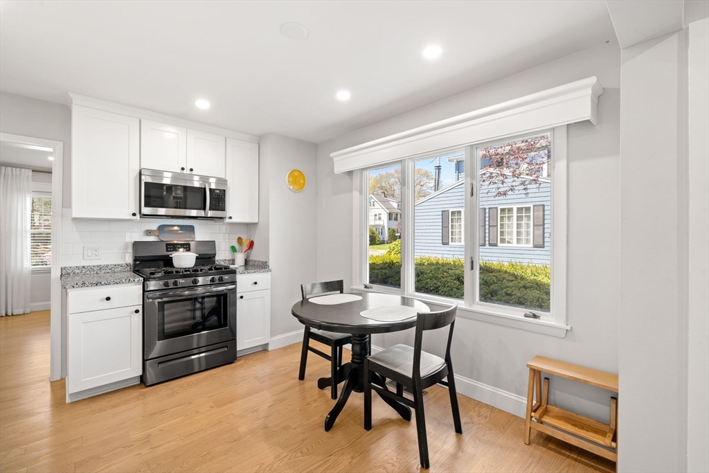 76 Perkins Street Stoneham, MA 02180 - Photo 12 of 40 a kitchen with stainless steel appliances granite countertop a stove top oven a sink a refrigerator with a dining table and chairs