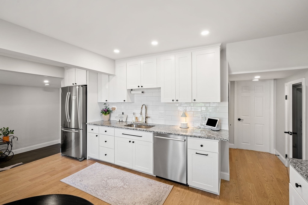 76 Perkins Street Stoneham, MA 02180 - Photo 13 of 40 a kitchen with stainless steel appliances granite countertop a refrigerator sink and white cabinets