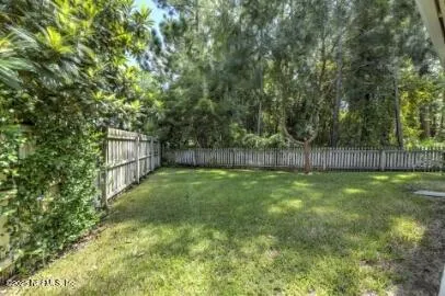 a view of a backyard with large trees and wooden fence