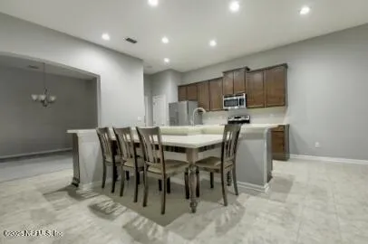 a kitchen with stainless steel appliances granite countertop a stove a sink a microwave a island with a dining table and chair