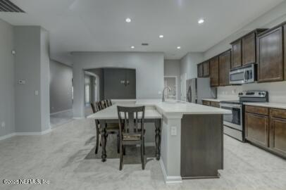 86192 Fortune Drive Yulee, FL 32097 - Photo 15 of 33 a kitchen with stainless steel appliances granite countertop a stove a sink a microwave a island with a dining table and chair