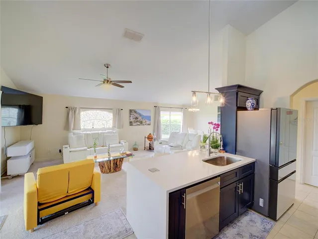 a view of living room kitchen with stainless steel appliances kitchen island furniture and a window
