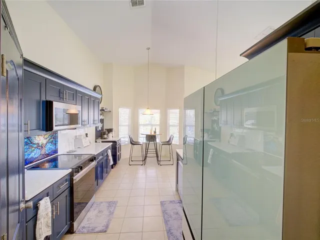 a large living room with stainless steel appliances a couch and a large window