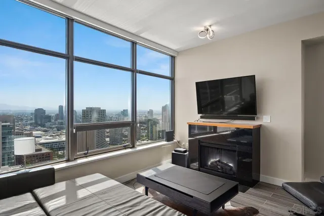 a living room with a fireplace a flat screen tv and a floor to ceiling window