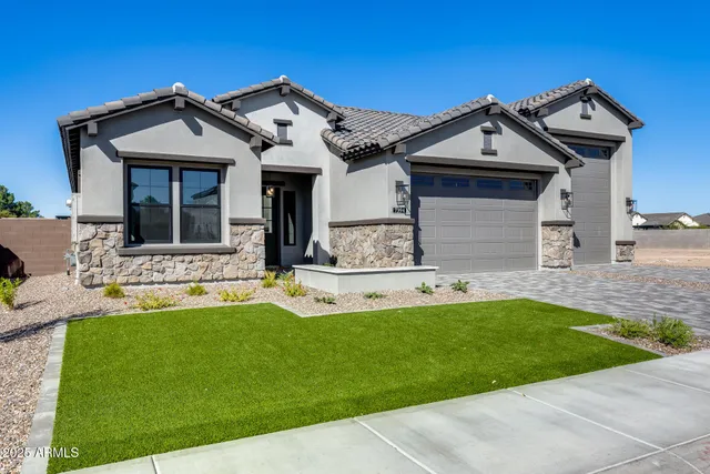 a view of a house with a yard plants and large tree