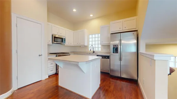 a kitchen with kitchen island a refrigerator sink and wooden floor