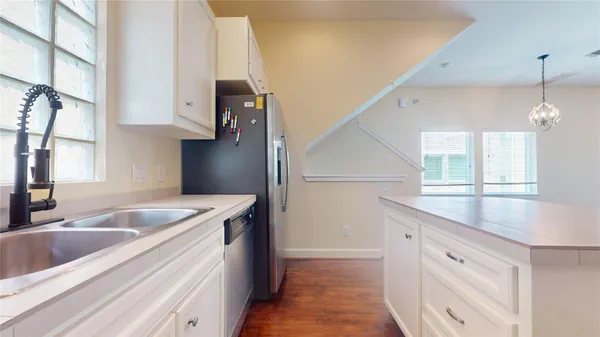 a kitchen with a sink dishwasher and white cabinets with wooden floor