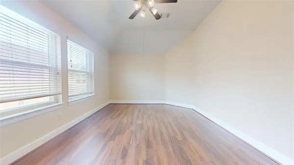 an empty room with wooden floor and windows