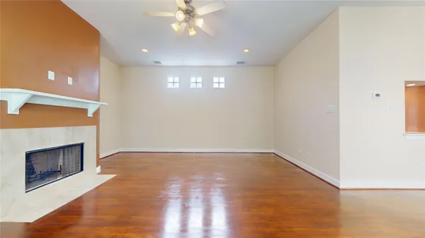 an empty room with wooden floor fireplace and windows