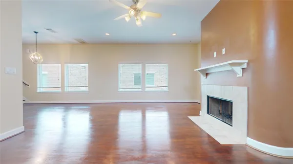 a view of an empty room with wooden floor and fireplace