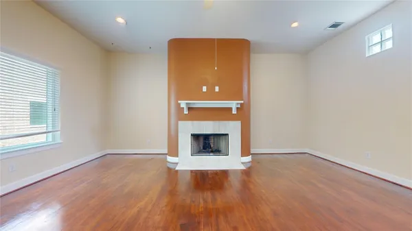 an empty room with wooden floor cabinet and windows