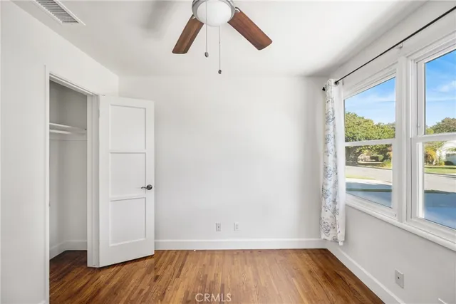a view of a big room with wooden floor and windows