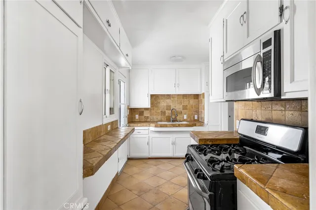 a white kitchen with granite countertop a sink and white cabinets