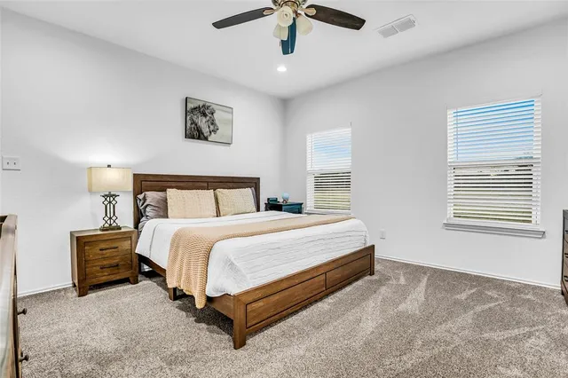 a bedroom with a bed painting on wall and windows