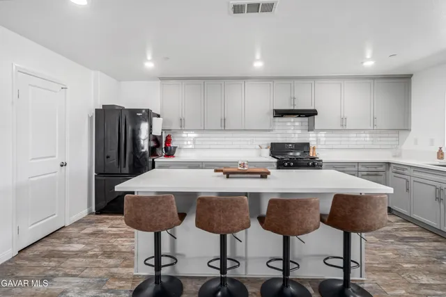 a kitchen with stainless steel appliances a dining table chairs refrigerator and cabinets
