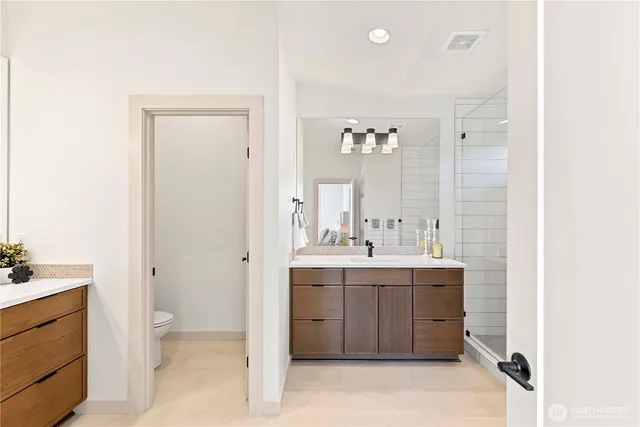 a spacious bathroom with a double vanity sink a mirror and a toilet