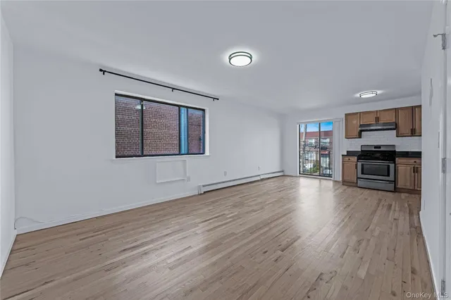 a view of empty room with kitchen and window