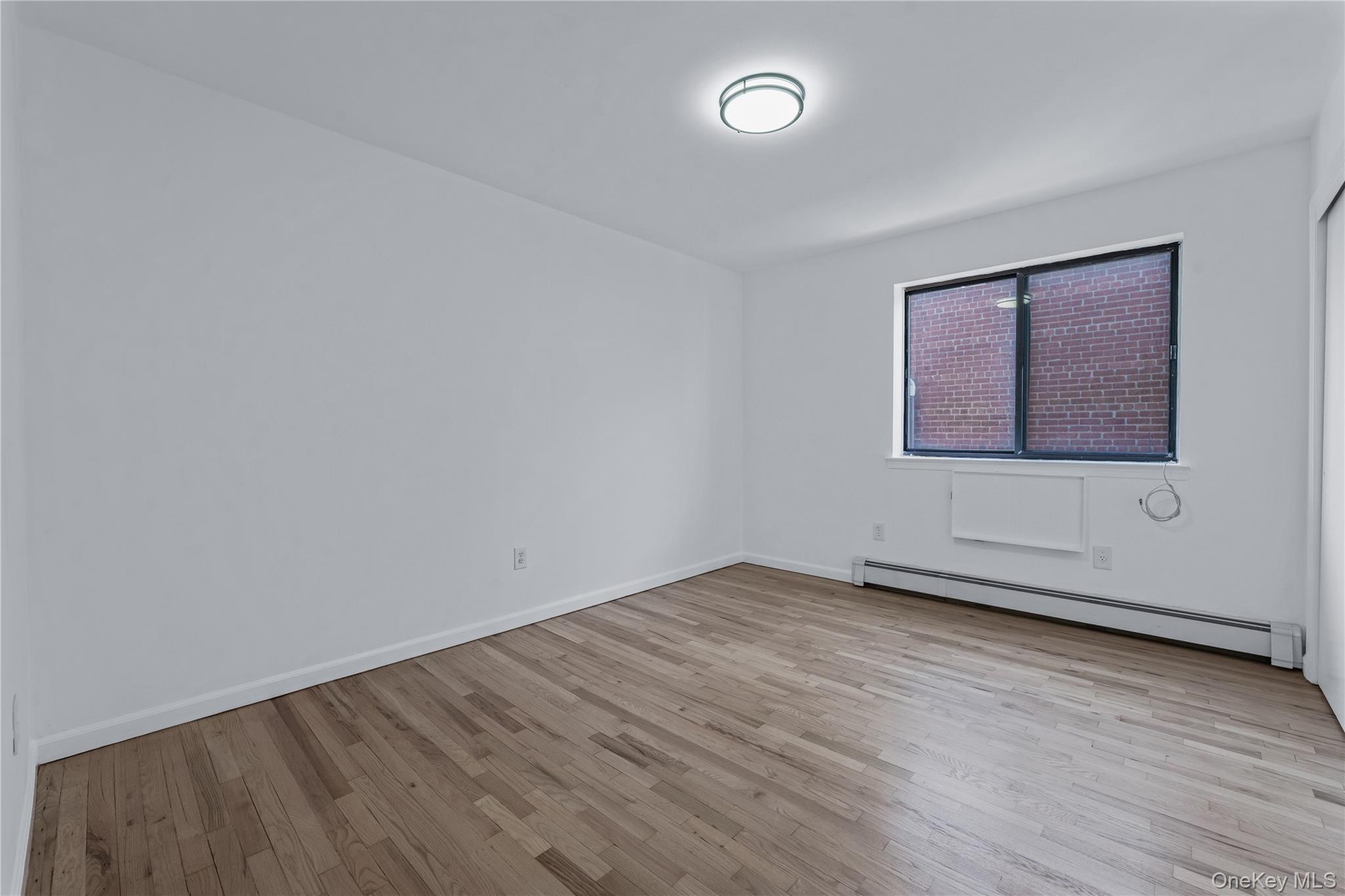 214-16 40th Avenue, Unit 3 Queens, NY 11361 - Photo 8 of 10 an empty room with wooden floor and windows