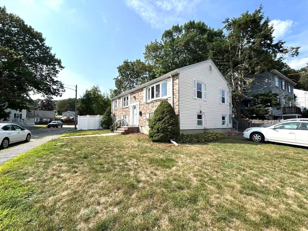 122 Running Brook Road Boston, MA 02132 - Photo 21 of 21 a view of a white house in front of a yard with potted plants and large trees