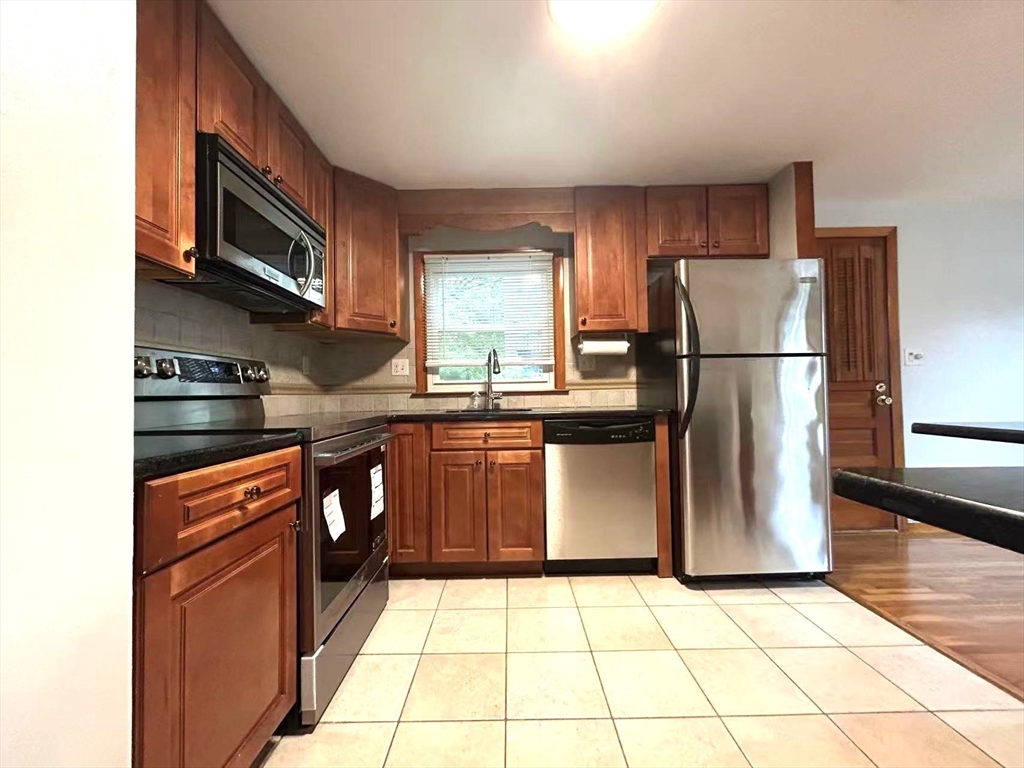 122 Running Brook Road Boston, MA 02132 - Photo 3 of 21 a kitchen with stainless steel appliances granite countertop a refrigerator stove a sink and a microwave