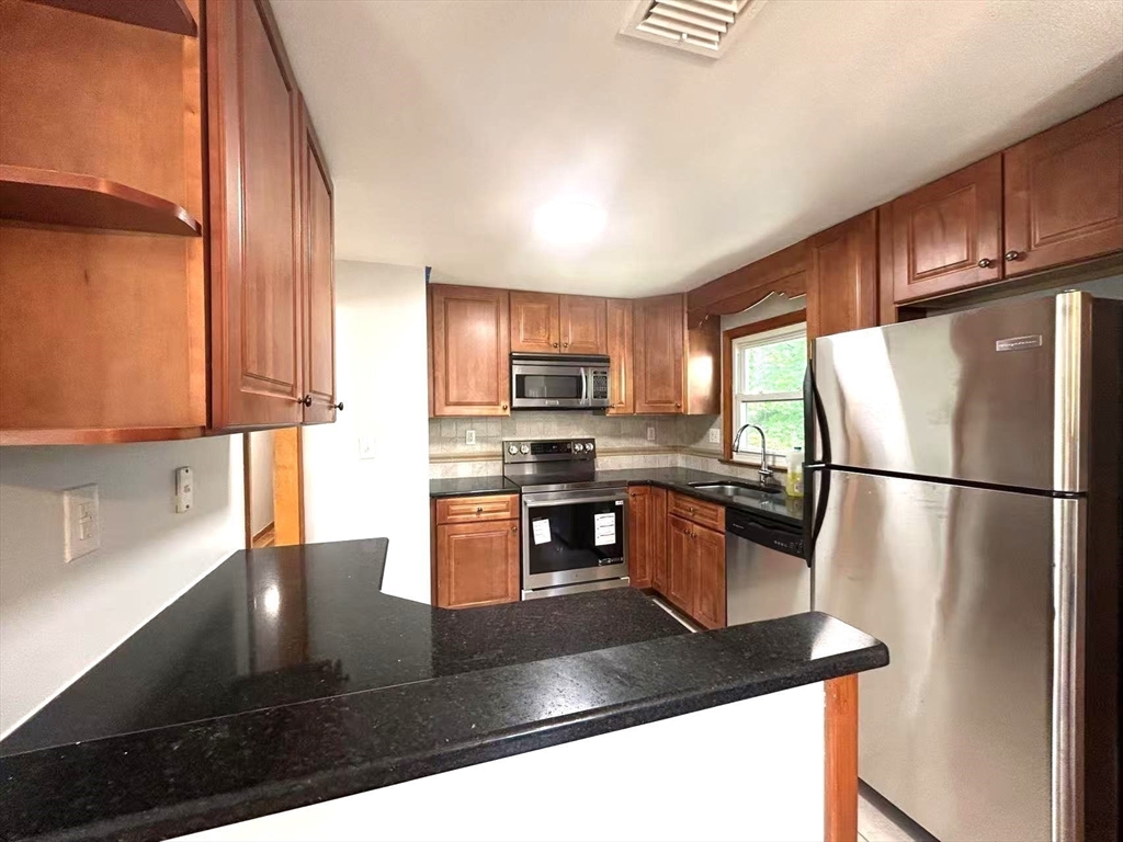 122 Running Brook Road Boston, MA 02132 - Photo 4 of 21 a kitchen with stainless steel appliances granite countertop a refrigerator a stove a sink a microwave and island