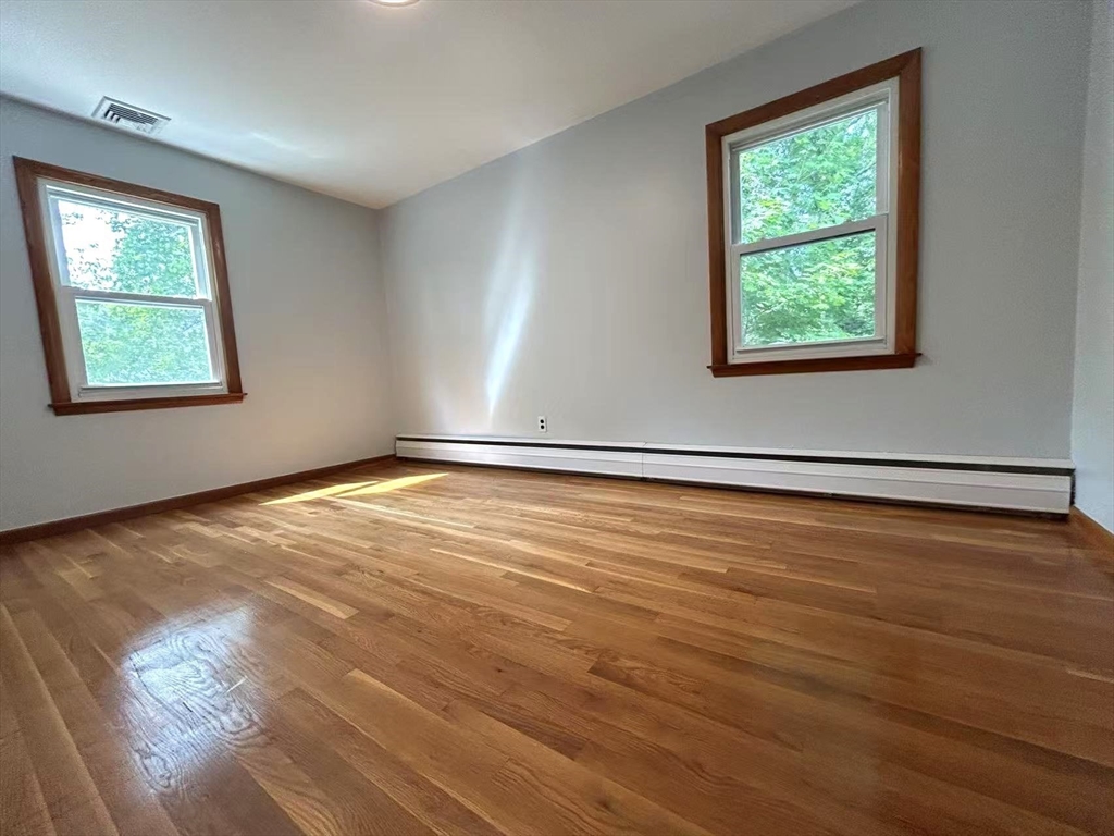 122 Running Brook Road Boston, MA 02132 - Photo 9 of 21 an empty room with wooden floor and windows