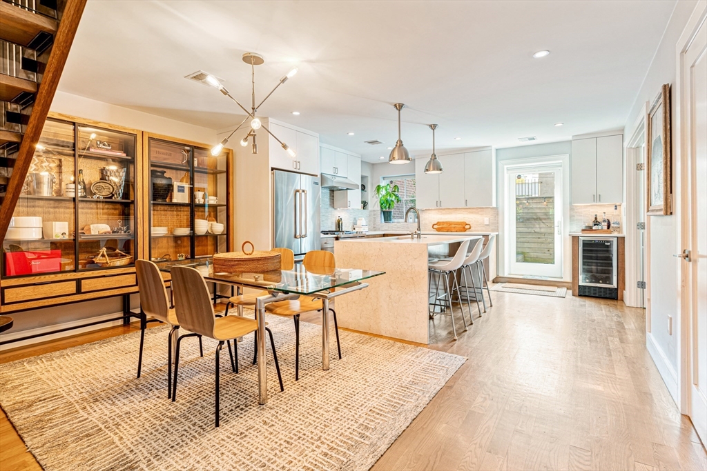 491 Massachusetts Avenue, Unit 1 Boston, MA 02118 - Photo 7 of 26 a dining hall with stainless steel appliances granite countertop a stove top oven a dining table and chairs with wooden floor