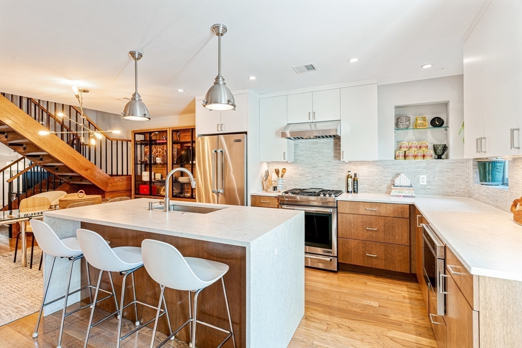 491 Massachusetts Avenue, Unit 1 Boston, MA 02118 - Photo 8 of 26 a open kitchen with stainless steel appliances kitchen island a table chairs in it and white cabinets