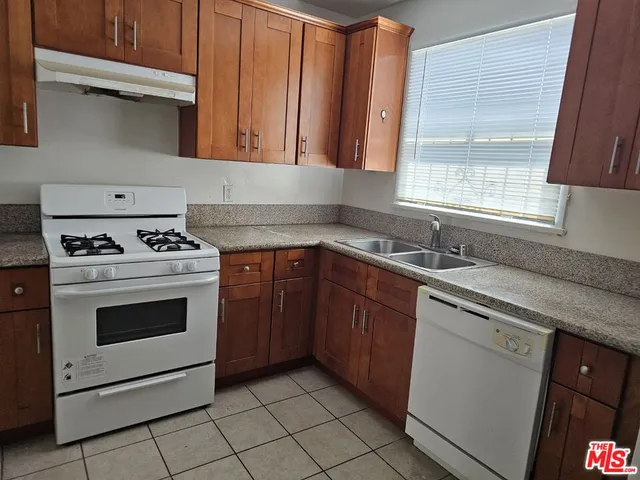 a kitchen with granite countertop a sink a stove and cabinets