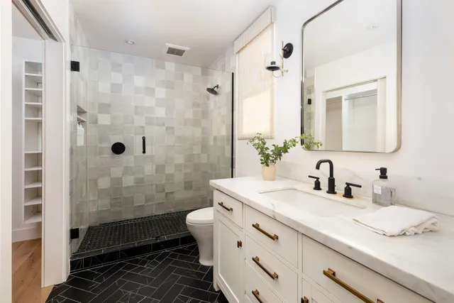 a bathroom with a granite countertop sink a toilet and shower