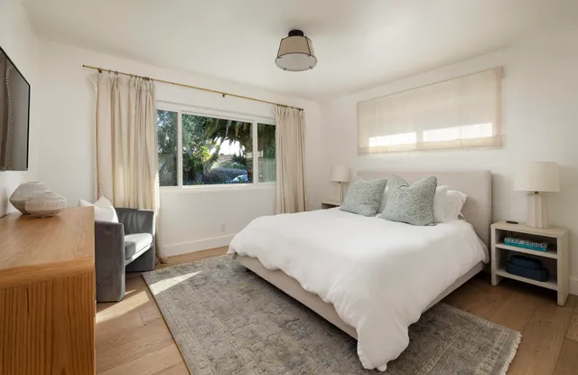 a bedroom with a bed wooden floor and window