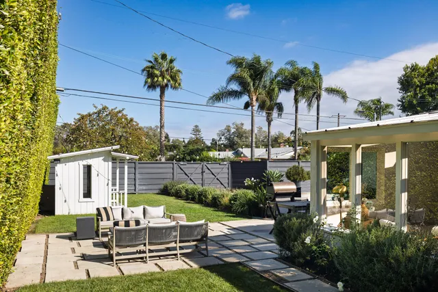 a view of a patio with couches table and chairs potted plants and palm tree