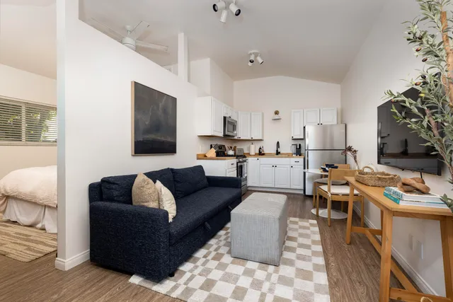 a living room with furniture kitchen view and a window