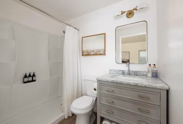 a bathroom with a granite countertop sink mirror vanity and toilet