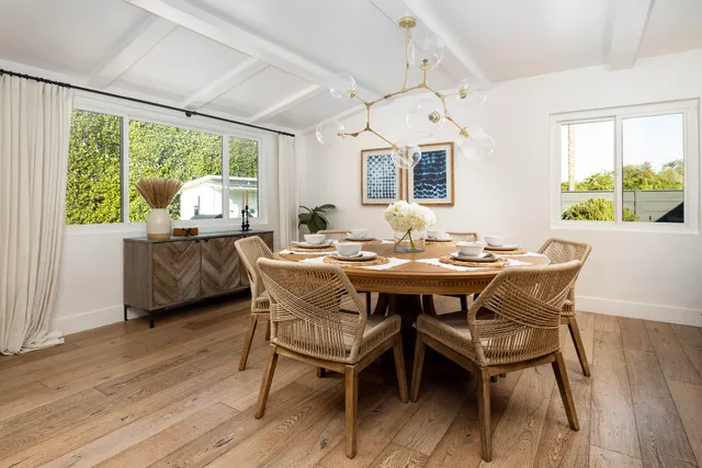 a dining room with furniture large windows and wooden floor