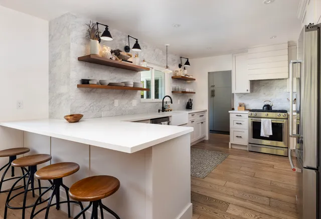 a kitchen with stainless steel appliances a table and chairs in it
