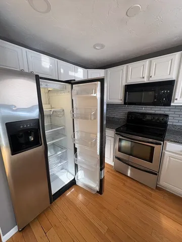 a living room with stainless steel appliances wooden floor and a fireplace
