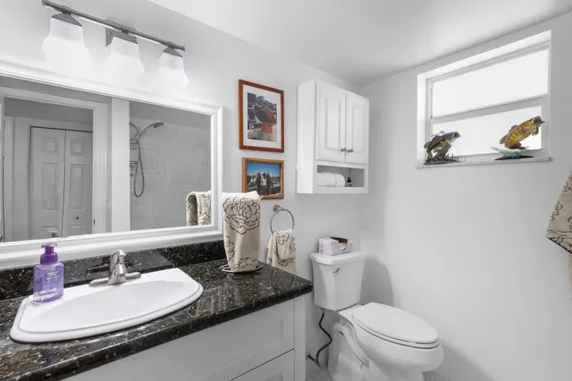 a bathroom with a granite countertop toilet a sink and a mirror