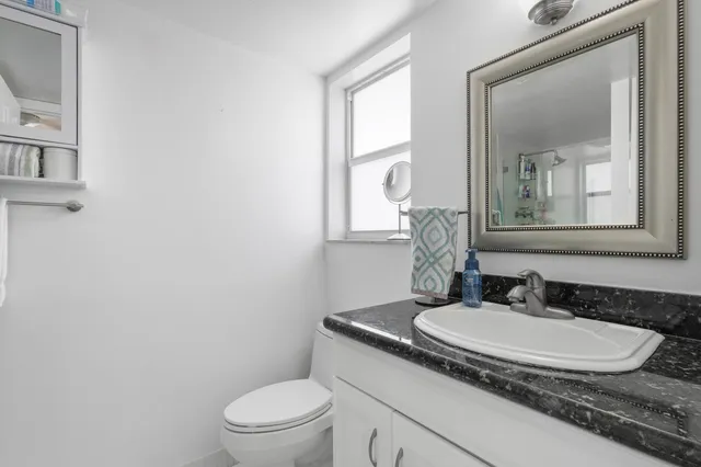 a bathroom with a granite countertop sink a toilet and a mirror