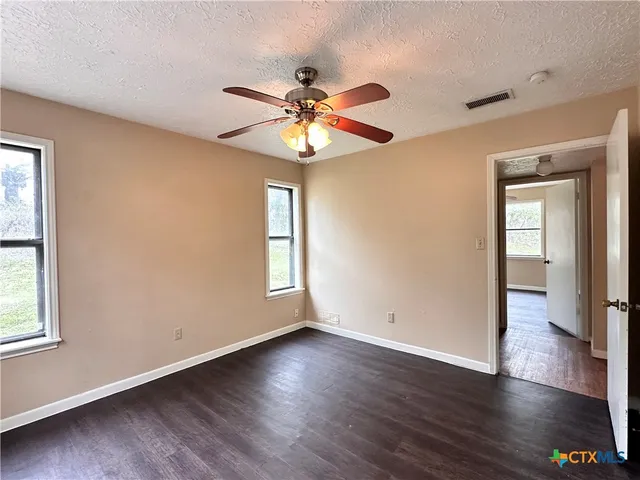 a view of an empty room with window and wooden floor